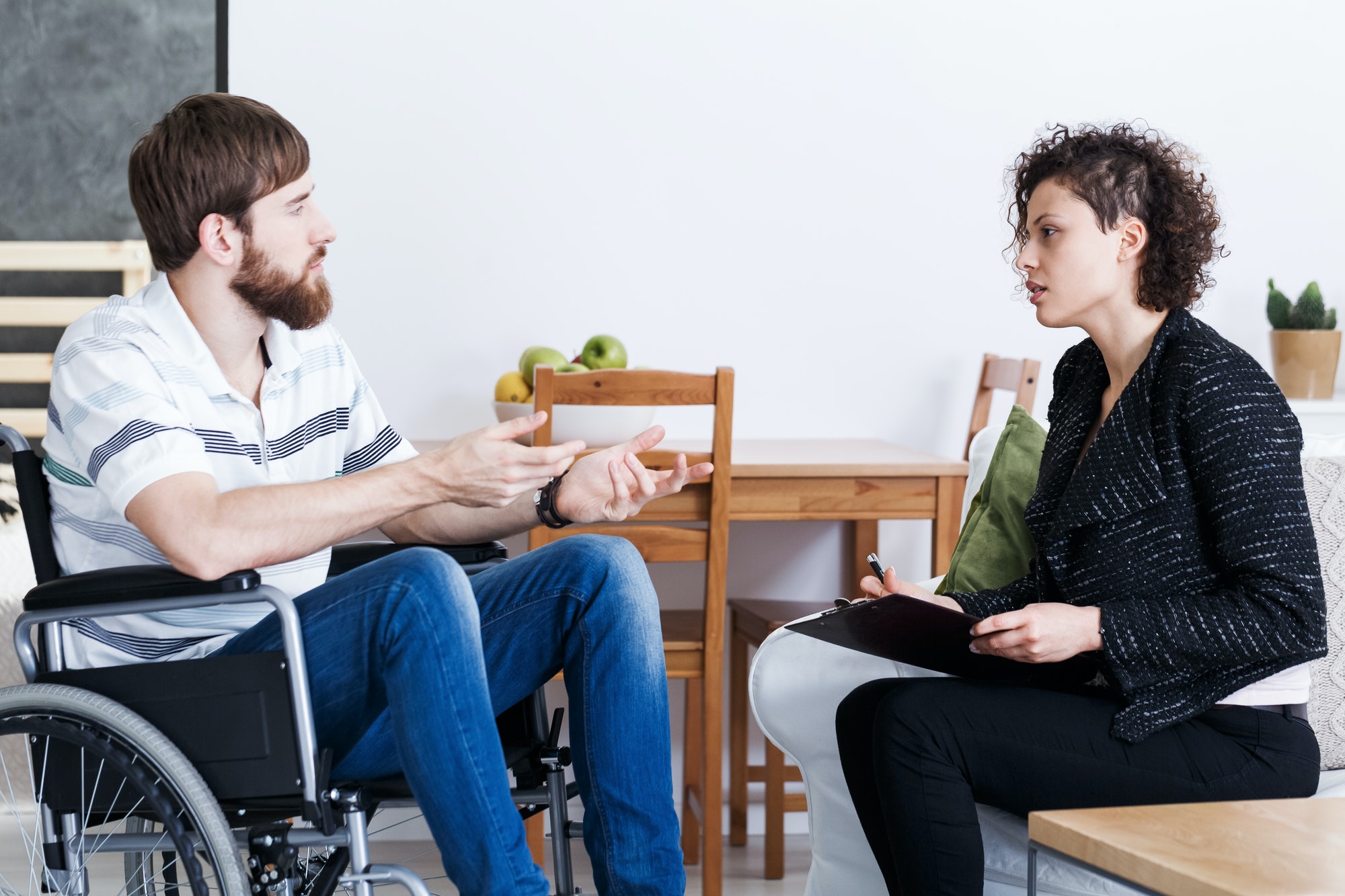 Man in wheelchair talking with psychotherapist